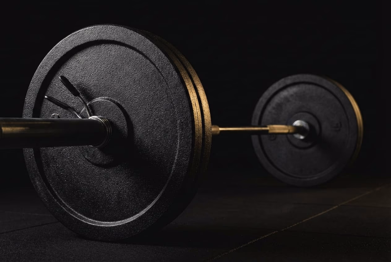 Close up of a heavy barbell in a dark gym setting representing the training phase and performance maintenance